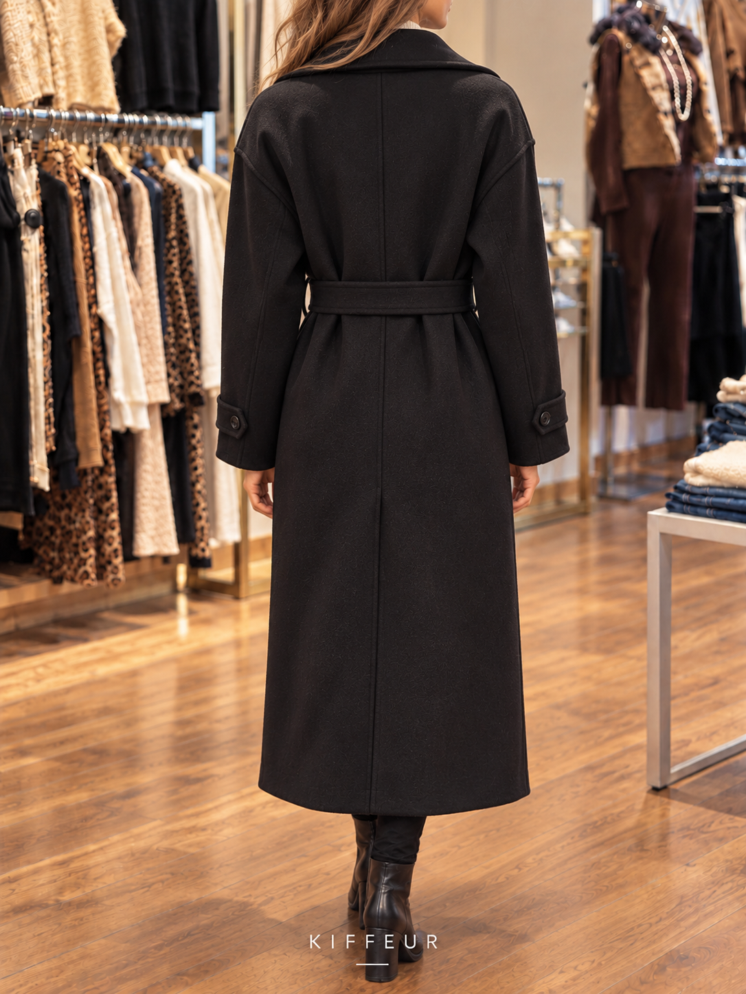 Manteau long ceinturé noir porté en boutique, vue de dos